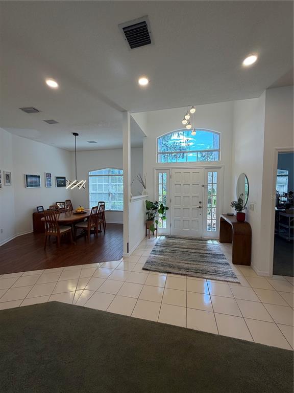 A foyer with tiled floors leads to a dining area with wood flooring and windows — 2435 SWEETWATER COUNTRY CLUB PLACE DRIVE, APOPKA, FL
