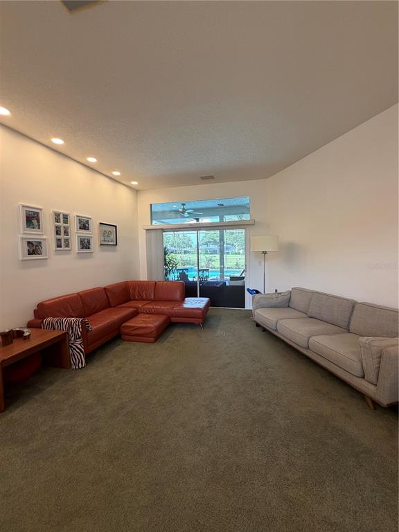A living room features a red sectional sofa, a gray sofa, and a large sliding door — 2435 SWEETWATER COUNTRY CLUB PLACE DRIVE, APOPKA, FL