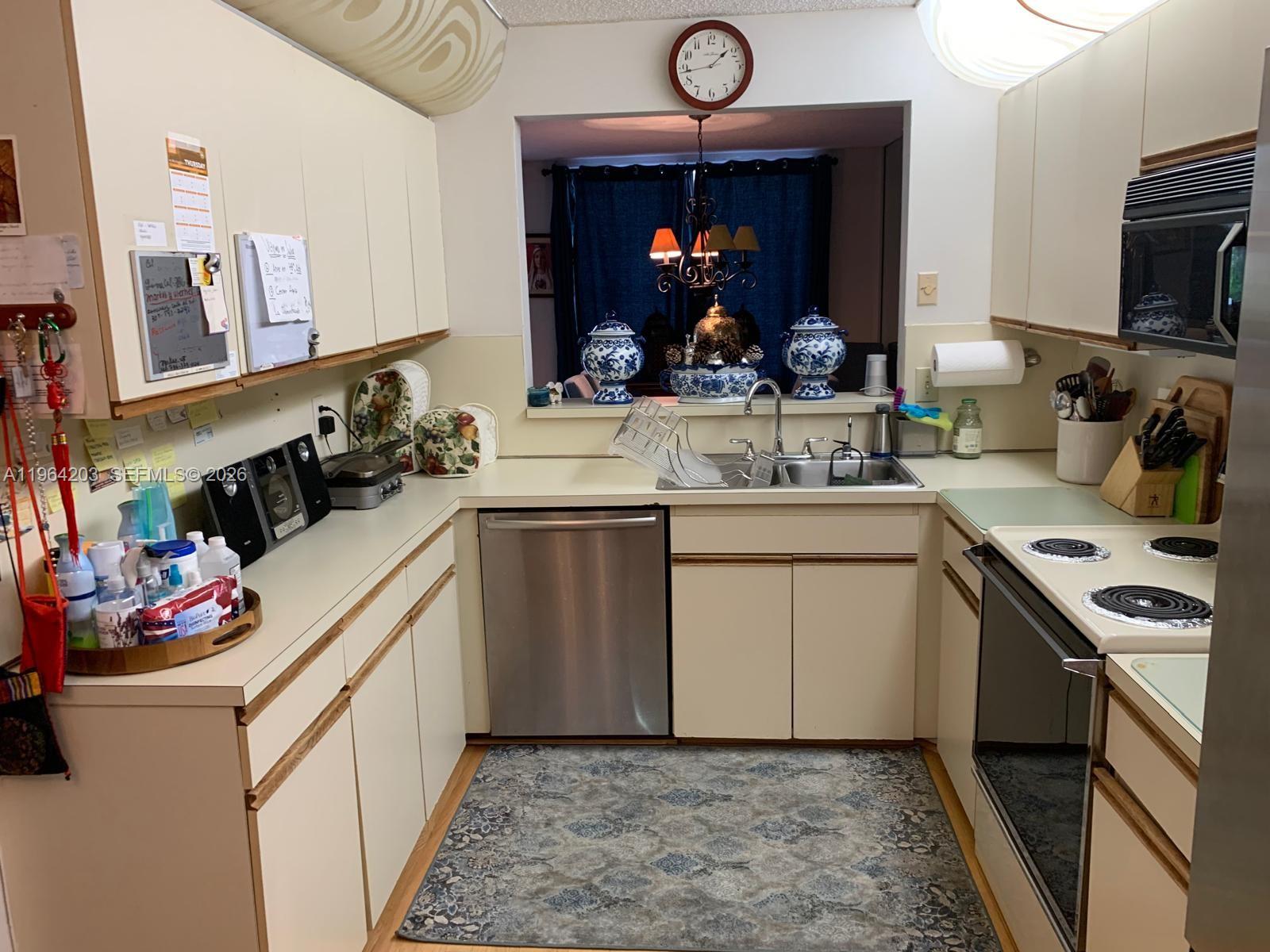 A kitchen features cream-colored cabinets, stainless steel appliances, and a pass-through window to a dining area — 3340 Torremolinos Ave # 40, Doral FL 33178, DORAL, FL