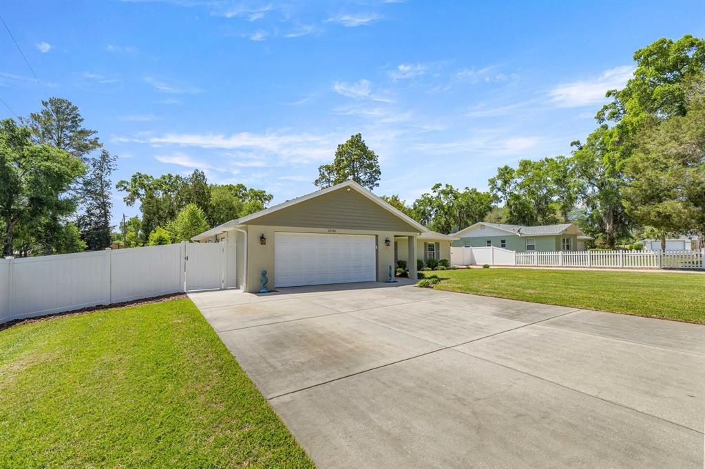 A light green house with a two-car garage and a white vinyl fence — 20430 SW 80TH PLACE ROAD, DUNNELLON, FL