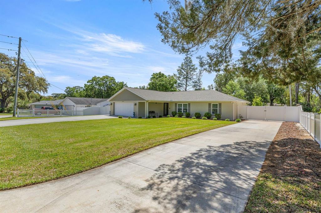 A single-story house with a light-colored exterior, a two-car garage, and a long concrete driveway — 20430 SW 80TH PLACE ROAD, DUNNELLON, FL