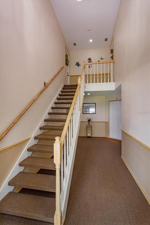 A carpeted staircase with a wooden railing leads to an upper landing in a hallway — 5301 WHITE CLIFF LANE UNIT 7, ORLANDO, FL