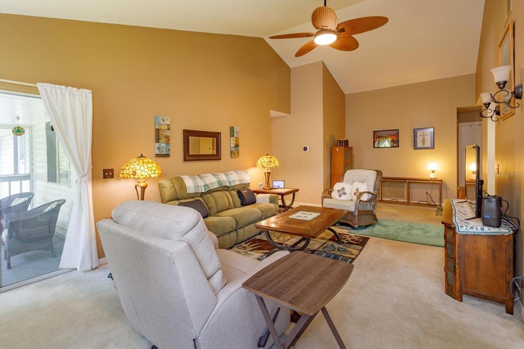 A living room features vaulted ceilings, a ceiling fan, a green sofa, and a recliner — 5301 WHITE CLIFF LANE UNIT 7, ORLANDO, FL