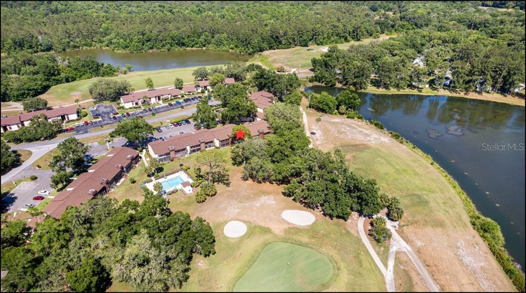 An aerial view shows a multi-unit residential building situated next to a golf course pond — 749 MIDWAY DRIVE UNIT A, OCALA, FL
