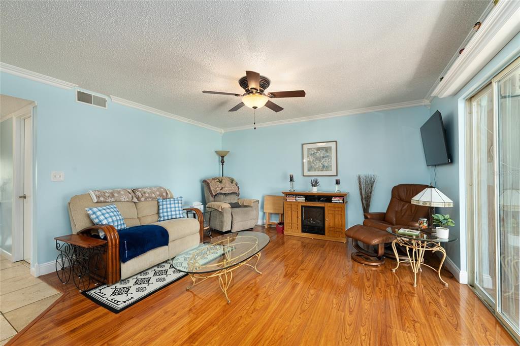 A living room features light blue walls, wood flooring, a ceiling fan, and various furniture — 749 MIDWAY DRIVE UNIT A, OCALA, FL