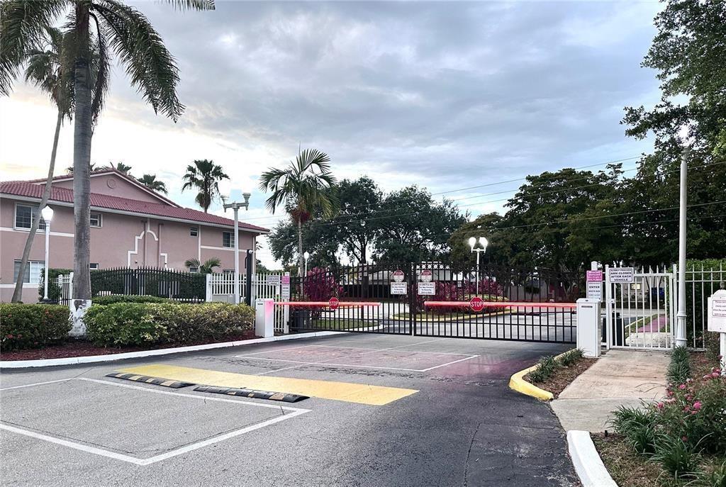 A gated entrance with a metal security barrier and a speed bump in the foreground — 3241 Sabal Palm Manor # 104, Davie FL 33024, DAVIE, FL