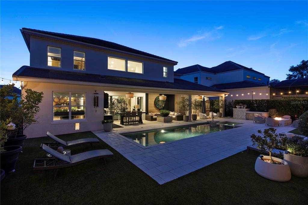 A two-story house exterior features a swimming pool, covered patio, and landscaped backyard at dusk — 1659 CANYON OAK WAY, SANFORD, FL