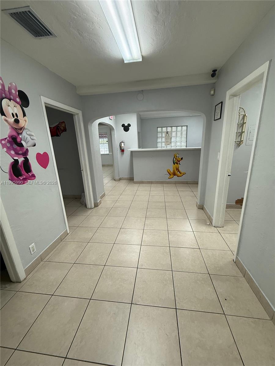 This interior view shows a tiled hallway leading to a reception desk with Disney-themed wall decals — 4141 SW 6th St, Miami FL 33134, MIAMI, FL