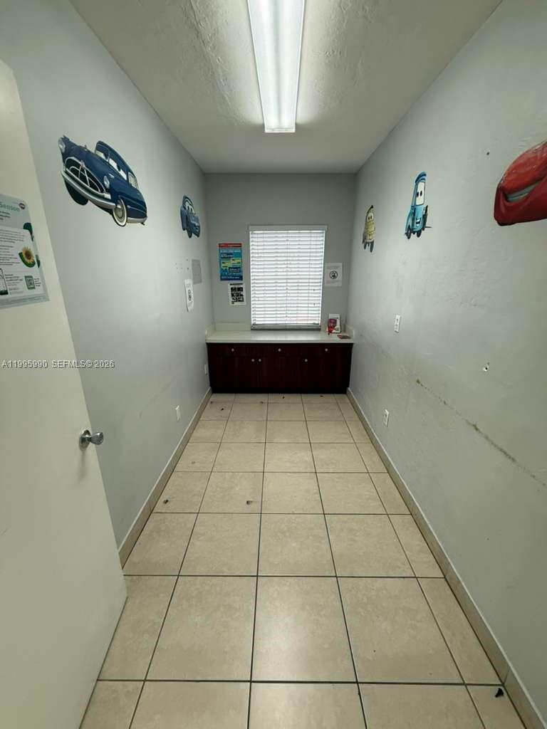 This narrow room features tiled flooring, dark wood cabinets, and wall decals of cars — 4141 SW 6th St, Miami FL 33134, MIAMI, FL