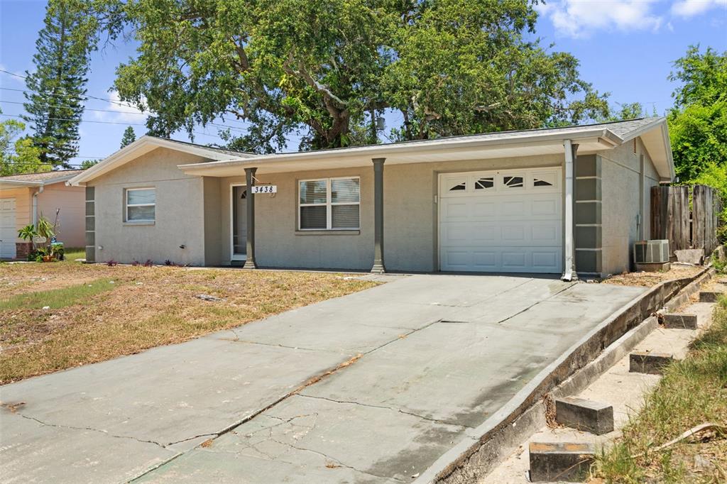 A single-story house with a concrete driveway, a garage, and a large tree in front — 3438 KIMBERLY OAKS DRIVE, HOLIDAY, FL