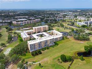An aerial view shows a multi-story apartment complex surrounded by a golf course and ponds — 4410 FAIRWAYS BOULEVARD UNIT 602-11, BRADENTON, FL