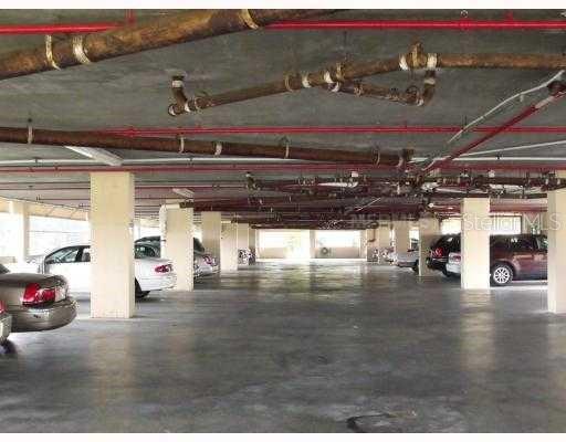 This is a covered parking garage with concrete pillars and exposed overhead pipes — 4410 FAIRWAYS BOULEVARD UNIT 602-11, BRADENTON, FL