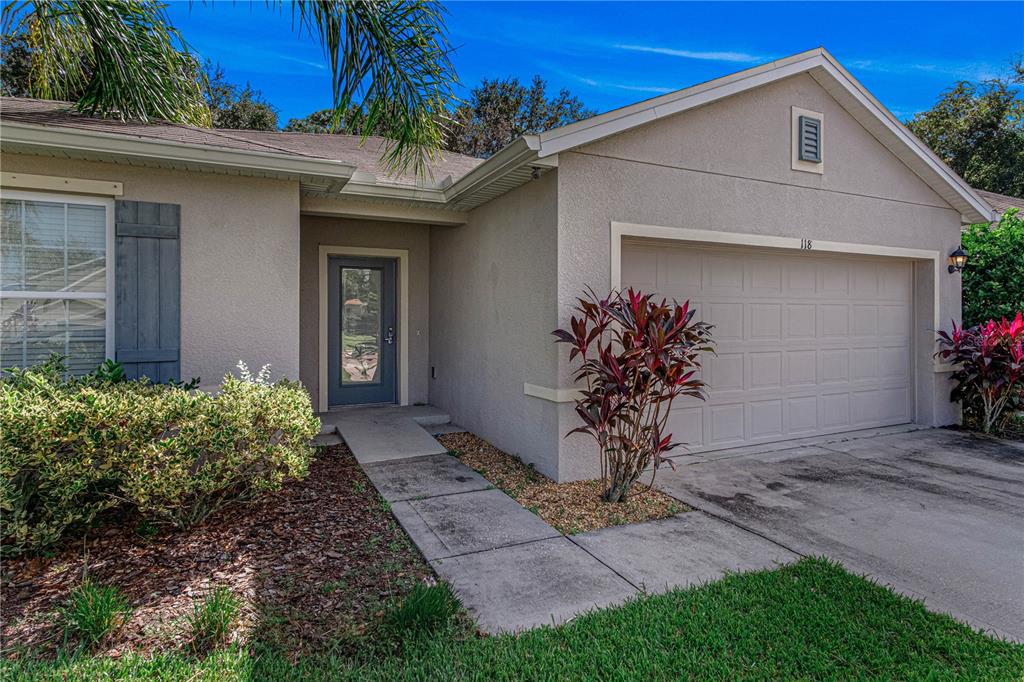 A single-story house exterior features a beige stucco facade, a garage, and a front entrance — 118 FISHERMANS COVE DRIVE, EDGEWATER, FL