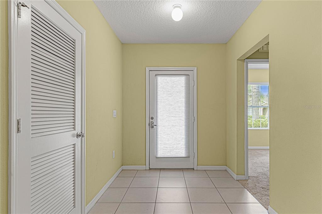 An entryway with light yellow walls, tiled flooring, a white door, and a louvered closet door — 118 FISHERMANS COVE DRIVE, EDGEWATER, FL