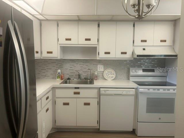 A kitchen features white cabinets, a stainless steel refrigerator, a white stove, and tiled backsplash — 7461 W COUNTRY CLUB DRIVE N UNIT 402, SARASOTA, FL