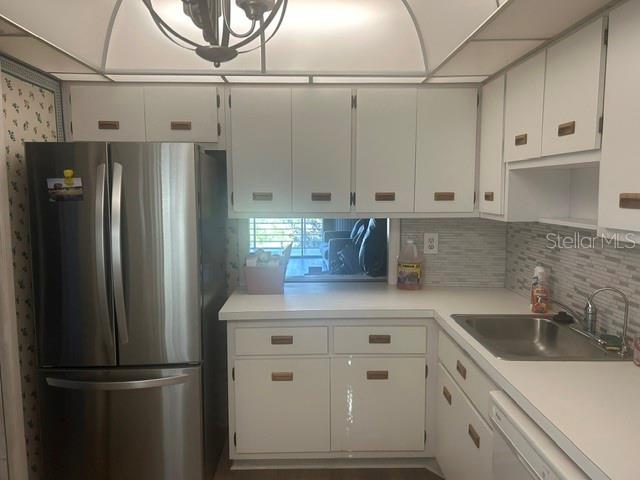 A kitchen features white cabinets, a stainless steel refrigerator, and a sink with tiled backsplash — 7461 W COUNTRY CLUB DRIVE N UNIT 402, SARASOTA, FL