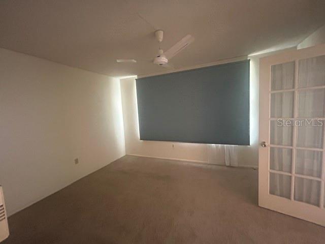 An empty room features beige carpeting, white walls, a ceiling fan, and a glass-paneled door — 7461 W COUNTRY CLUB DRIVE N UNIT 402, SARASOTA, FL