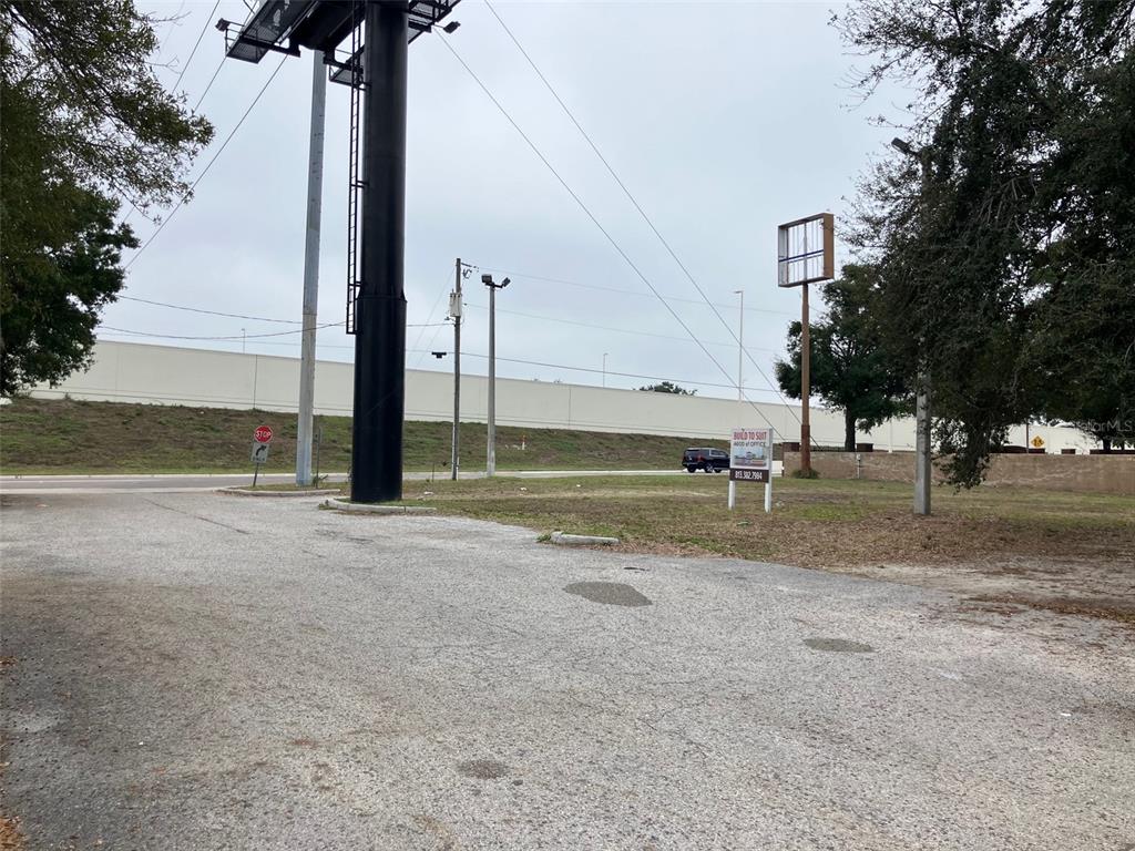A gravel lot features a large billboard, a small real estate sign, and a highway embankment — 3900 N MARGUERITE AVENUE, TAMPA, FL