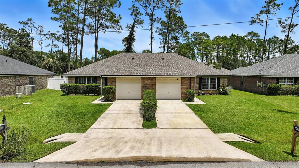 A single-story duplex with two garage doors and a shared concrete driveway — 70 RED MILL DRIVE, PALM COAST, FL