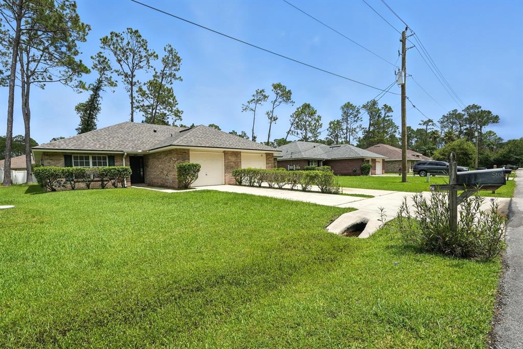 A single-story brick house with a two-car garage and a large front lawn — 70 RED MILL DRIVE, PALM COAST, FL