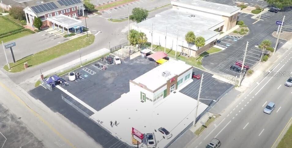 This aerial view shows a commercial building with a parking lot and surrounding streets — 5047 W COLONIAL DRIVE, ORLANDO, FL