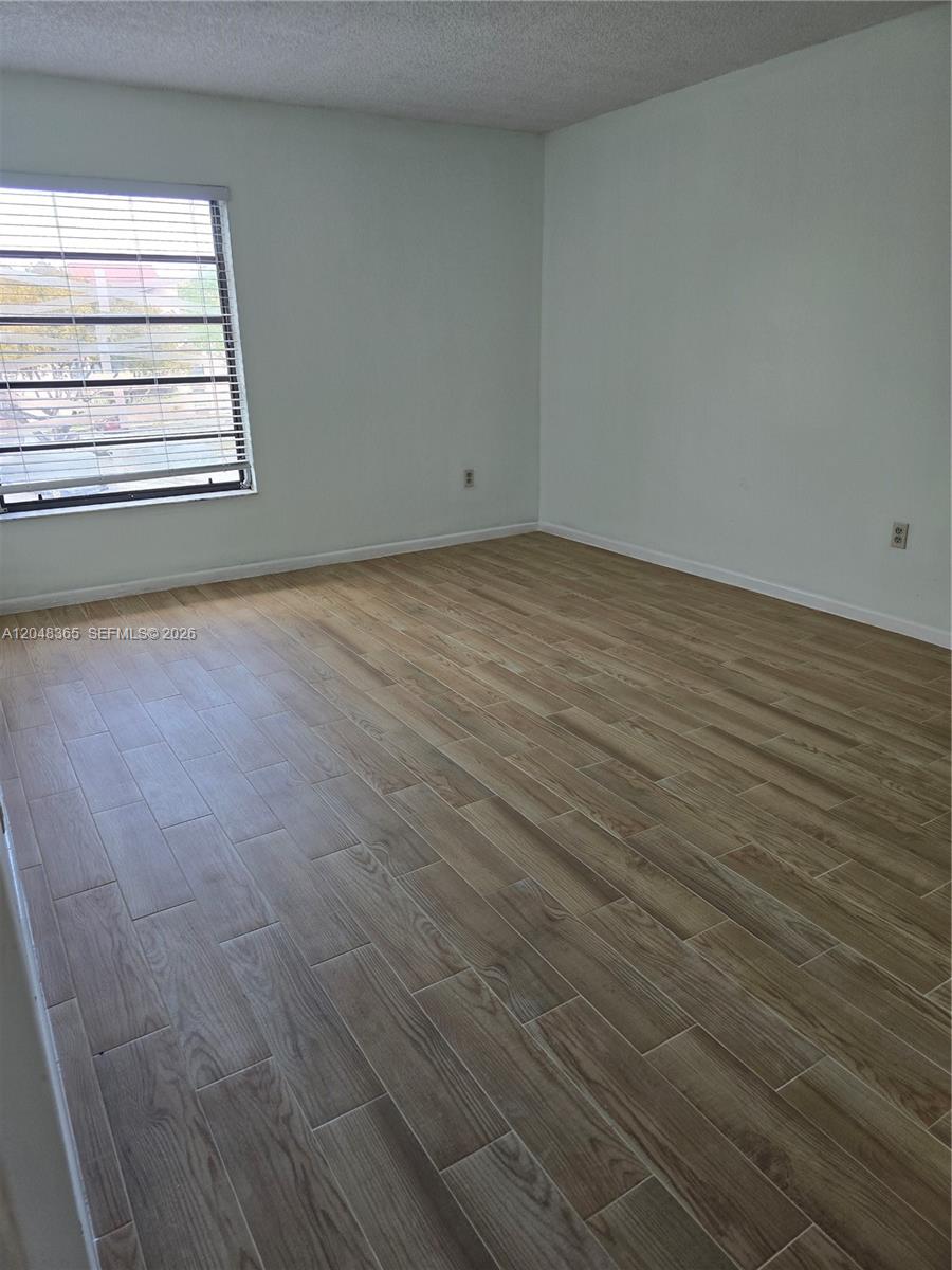 An empty room features light wood-look tile flooring, white walls, and a window with blinds — 5800 SW 127th Ave # 2310, Miami FL 33183, MIAMI, FL