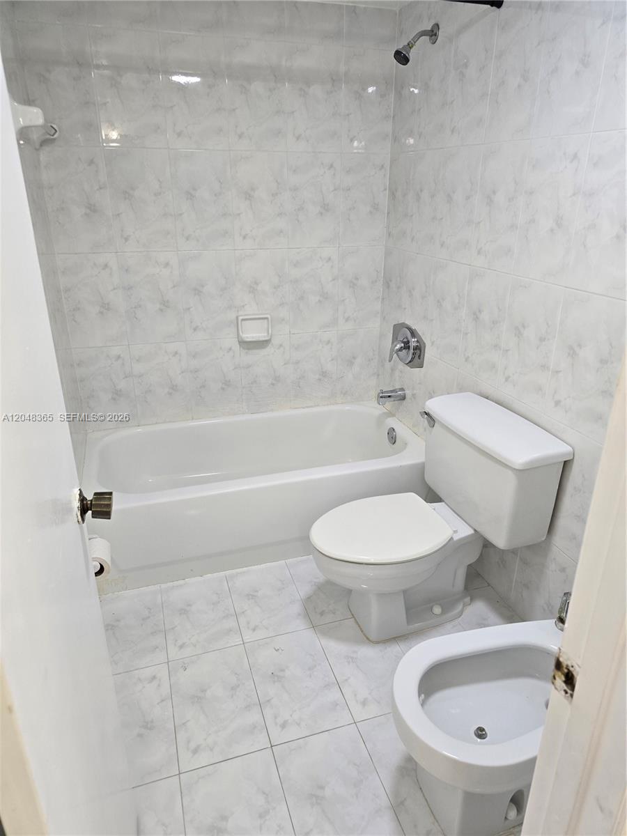 A bathroom features a white bathtub, a toilet, and a bidet with tiled walls — 5800 SW 127th Ave # 2310, Miami FL 33183, MIAMI, FL