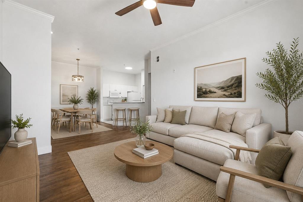 A bright living room features a beige sectional sofa, round coffee table, and open kitchen — 18106 PEREGRINES PERCH PLACE UNIT 5302, LUTZ, FL