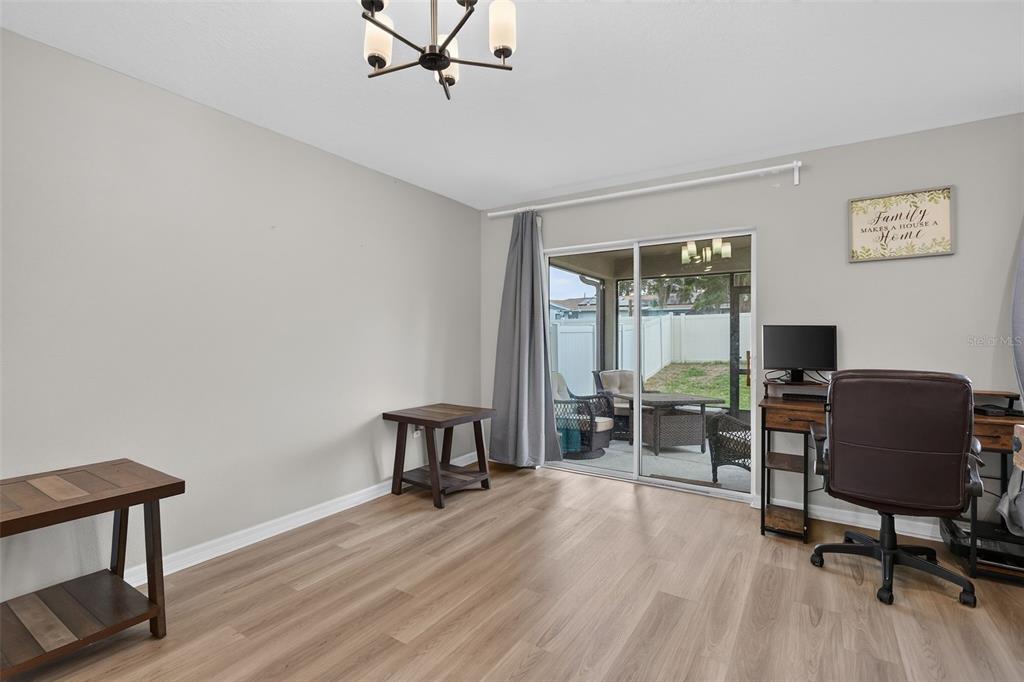 A room with light wood flooring, a desk, side tables, and a sliding glass door — 9972 MESIC WOODS AVENUE, SEFFNER, FL