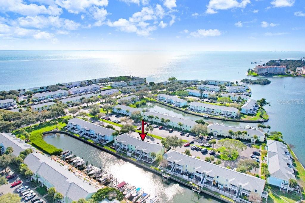 An aerial view shows a multi-story waterfront condominium complex with boat slips and parking — 5012 STARFISH DRIVE SE UNIT B, ST PETERSBURG, FL