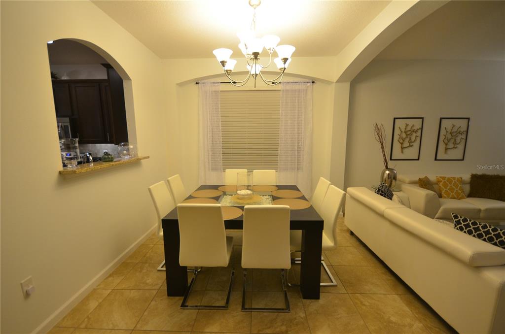 A beige two-car garage with a tiled roof and exterior wall-mounted lanterns — 2632 TRANQUILITY WAY, KISSIMMEE, FL