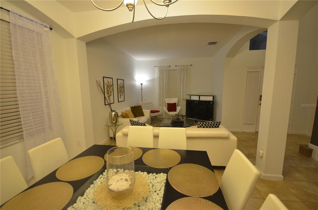 A living room features two white sofas, a glass coffee table, and a white chair — 2632 TRANQUILITY WAY, KISSIMMEE, FL