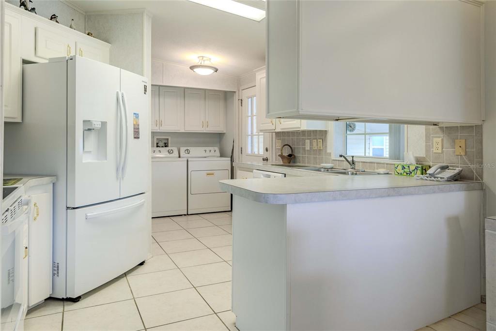 A kitchen with white cabinets, a refrigerator, laundry appliances, and a tiled floor — 2100 KINGS HIGHWAY UNIT 390, PORT CHARLOTTE, FL