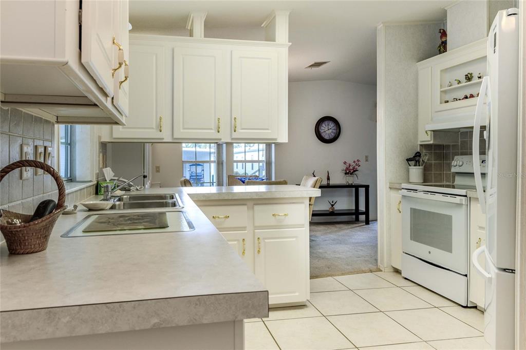 A kitchen features white cabinets, a light-colored countertop, and a white stove — 2100 KINGS HIGHWAY UNIT 390, PORT CHARLOTTE, FL
