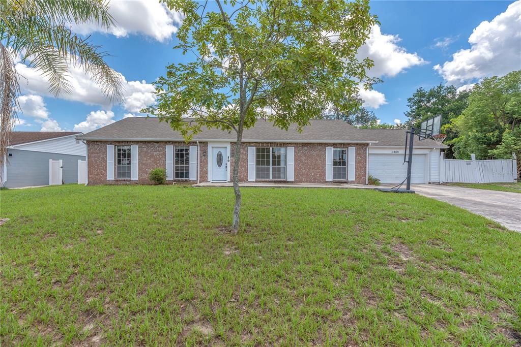 A single-story brick house with a white front door, shutters, and an attached garage — 1909 LIDO DRIVE, BRANDON, FL