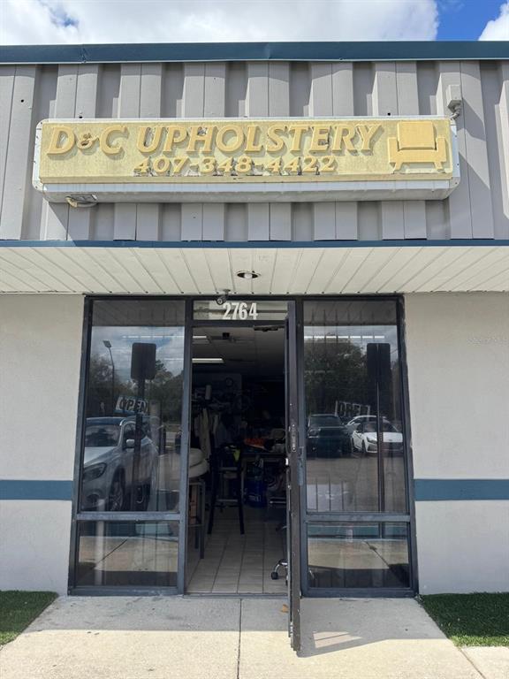 The exterior of a commercial building features a sign for D&C Upholstery above glass doors — 2764 N. ORANGE BLOSSOM TRAIL, KISSIMMEE, FL