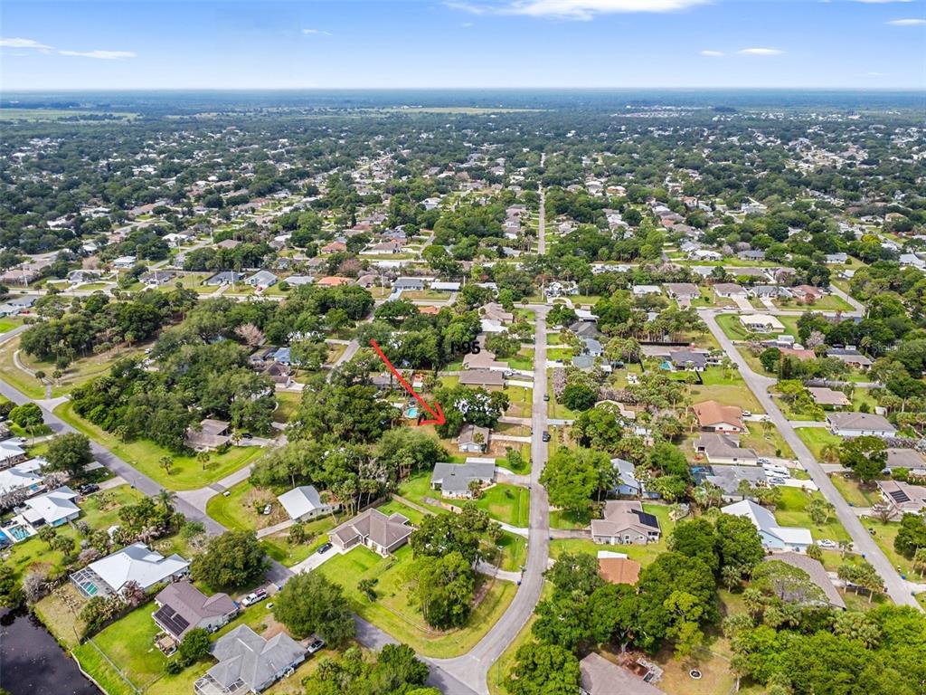 An aerial view shows a residential neighborhood with a red arrow pointing to a house — 326 BELFAST TERRACE, SEBASTIAN, FL