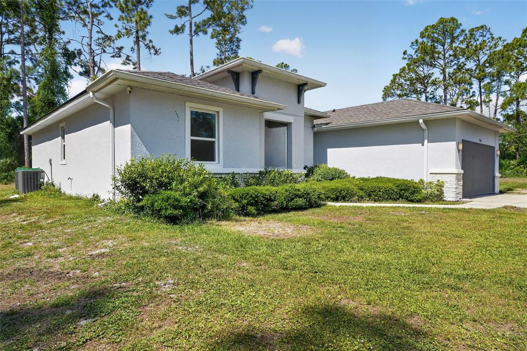 A light-colored single-story house with a gray garage door and a landscaped front yard — 5465 GAITOR TERRACE, NORTH PORT, FL