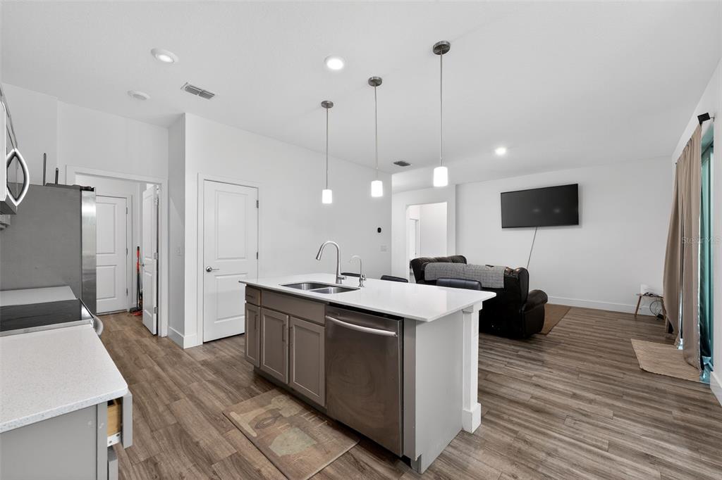 A kitchen island with a stainless steel dishwasher sits in an open-concept living area — 5465 GAITOR TERRACE, NORTH PORT, FL
