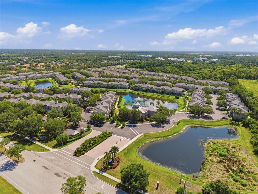 An aerial view of a residential community featuring multiple buildings, ponds, and landscaped grounds — 7560 PLANTATION CIRCLE, BRADENTON, FL