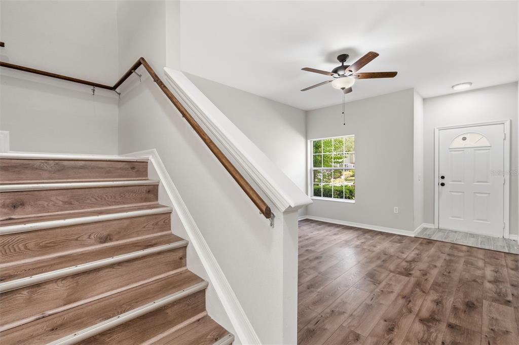 A staircase with wood-look steps and a handrail leads to a room with wood flooring — 7560 PLANTATION CIRCLE, BRADENTON, FL