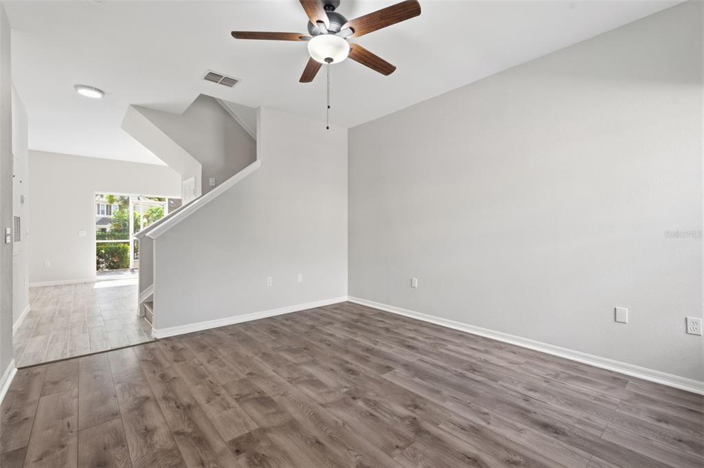 A living room with gray walls, wood-look flooring, a ceiling fan, and a staircase — 7560 PLANTATION CIRCLE, BRADENTON, FL
