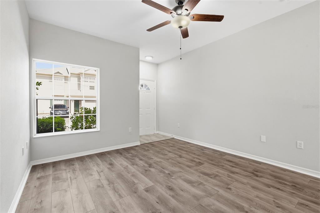 An empty room with light gray walls, wood-look flooring, a ceiling fan, and a window — 7560 PLANTATION CIRCLE, BRADENTON, FL