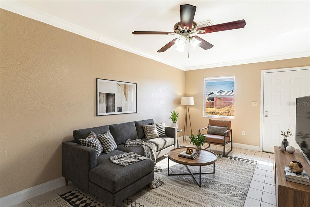A living room features a gray sectional sofa, a round coffee table, and a ceiling fan — 118 OAK CREST DRIVE NW, WINTER HAVEN, FL