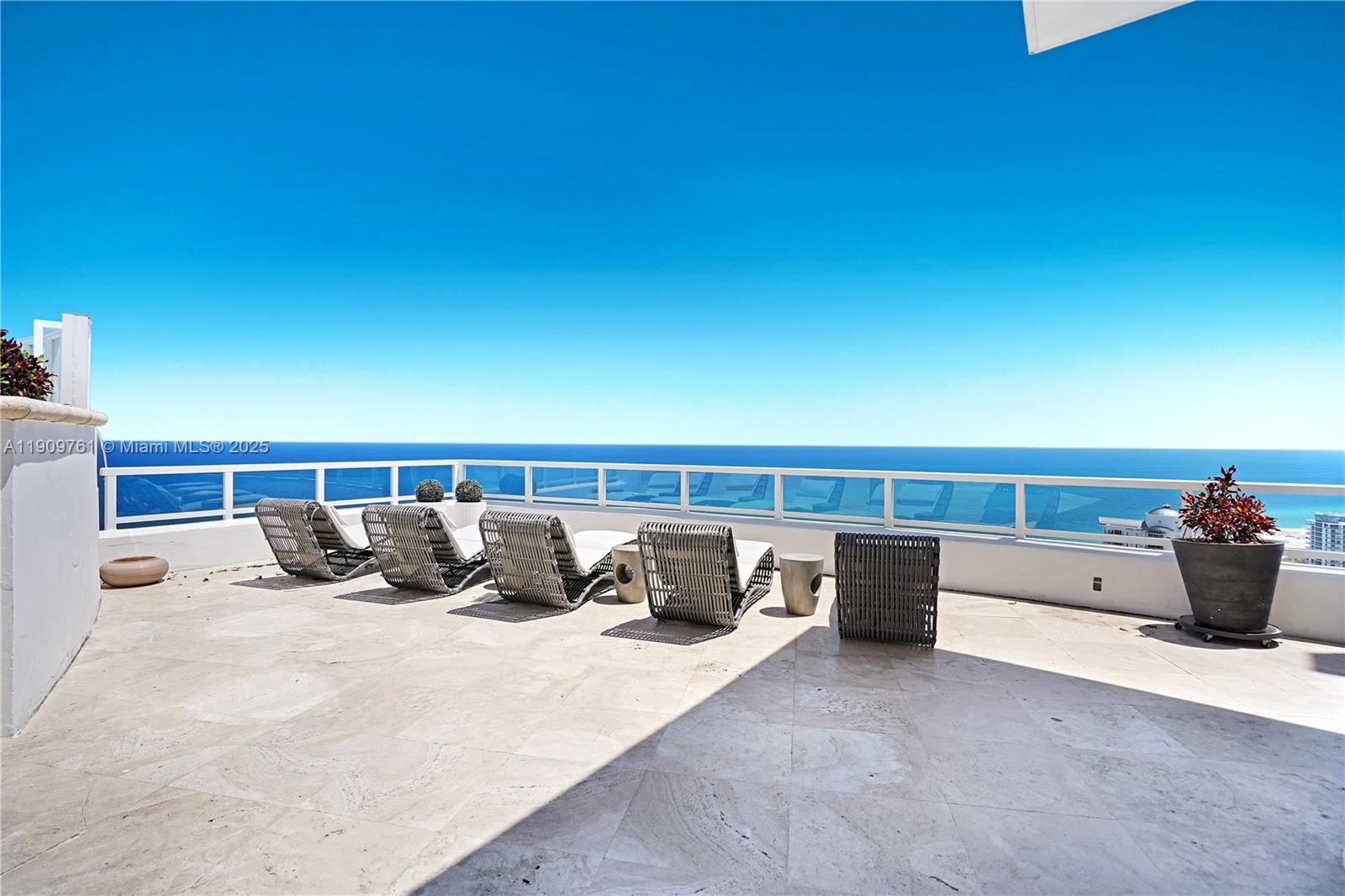 A spacious outdoor balcony features stone flooring, lounge chairs, and a glass railing overlooking the ocean — 4401 Collins Ave, Miami Beach FL 33140, MIAMI BEACH, FL