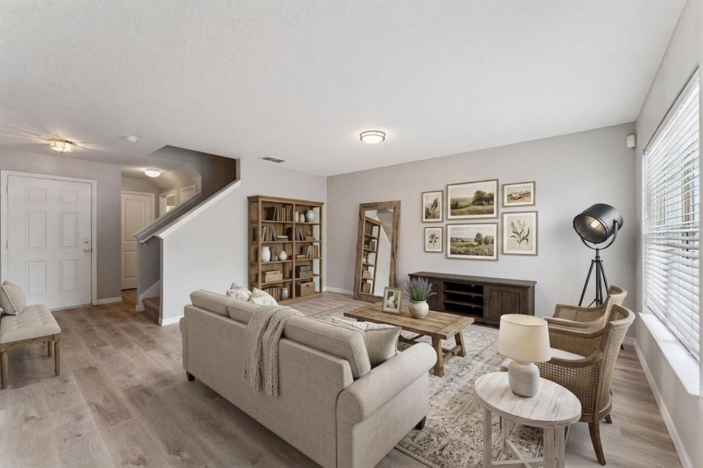 A living room features light wood flooring, a beige sofa, a media console, and a bookshelf — 3026 WILD TAMARIND BOULEVARD UNIT 3026, ORLANDO, FL