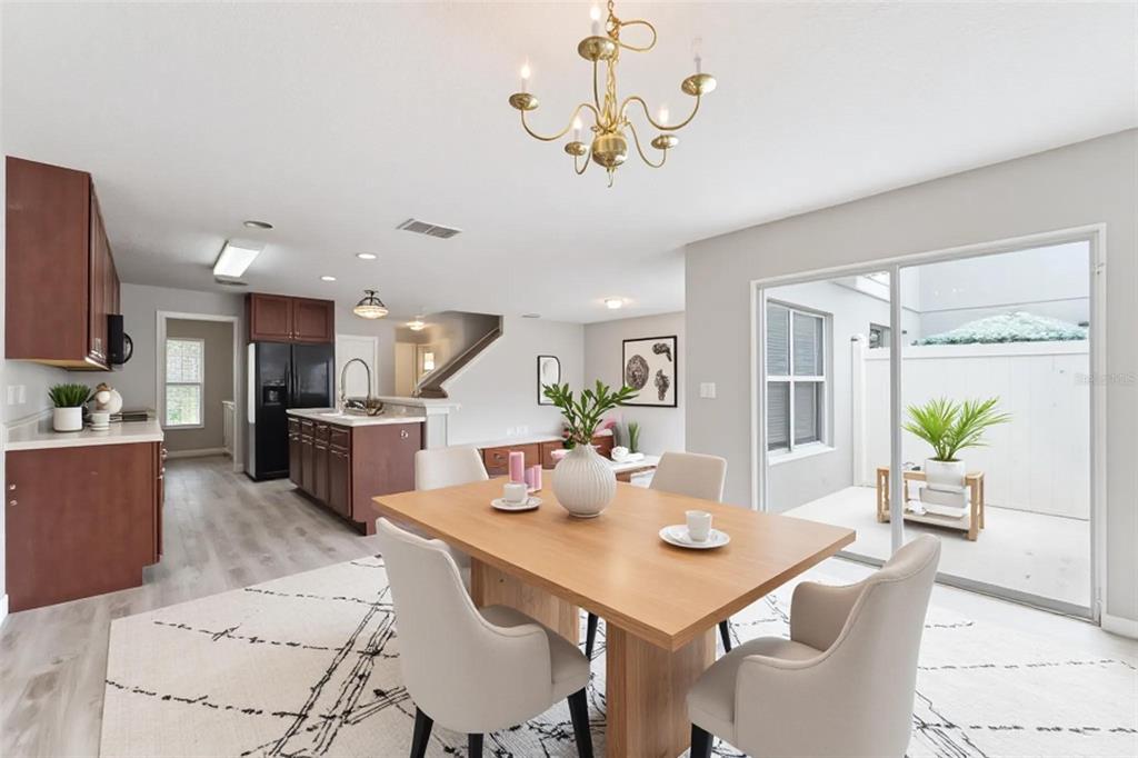 A dining area with a wooden table and chairs opens to a kitchen and patio — 3026 WILD TAMARIND BOULEVARD UNIT 3026, ORLANDO, FL