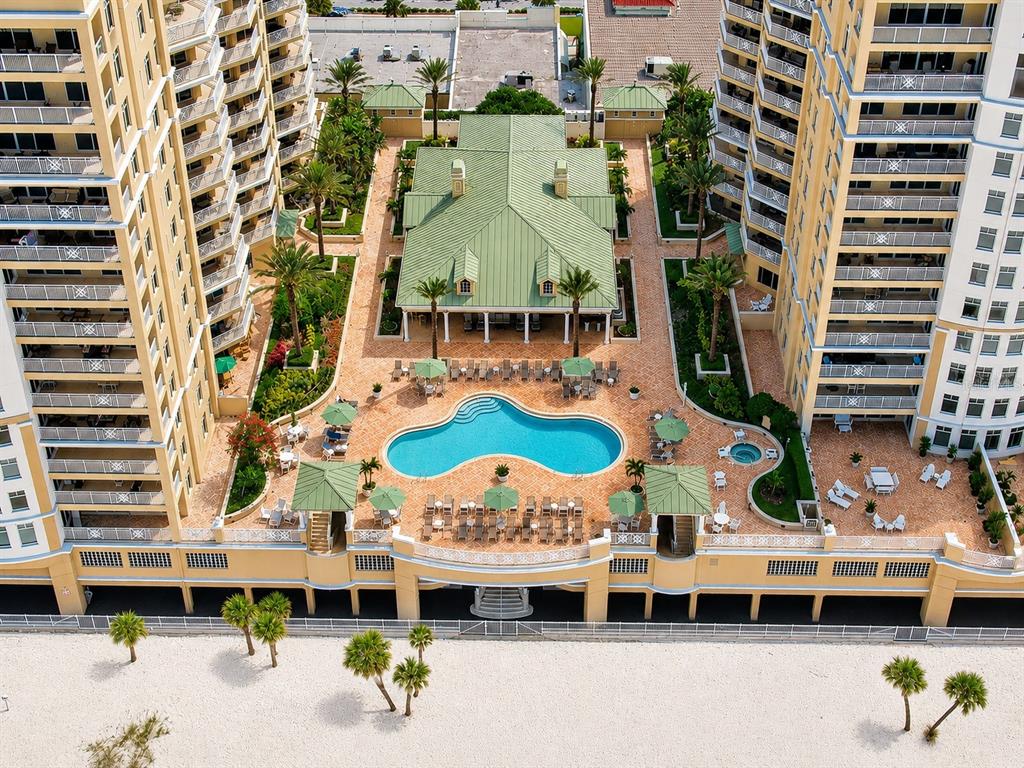 An aerial view of a swimming pool and clubhouse situated between two high-rise apartment buildings — 10 PAPAYA STREET UNIT 901, CLEARWATER BEACH, FL