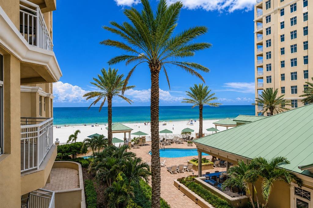 A view from a balcony overlooking a swimming pool, palm trees, and the ocean beach — 10 PAPAYA STREET UNIT 901, CLEARWATER BEACH, FL