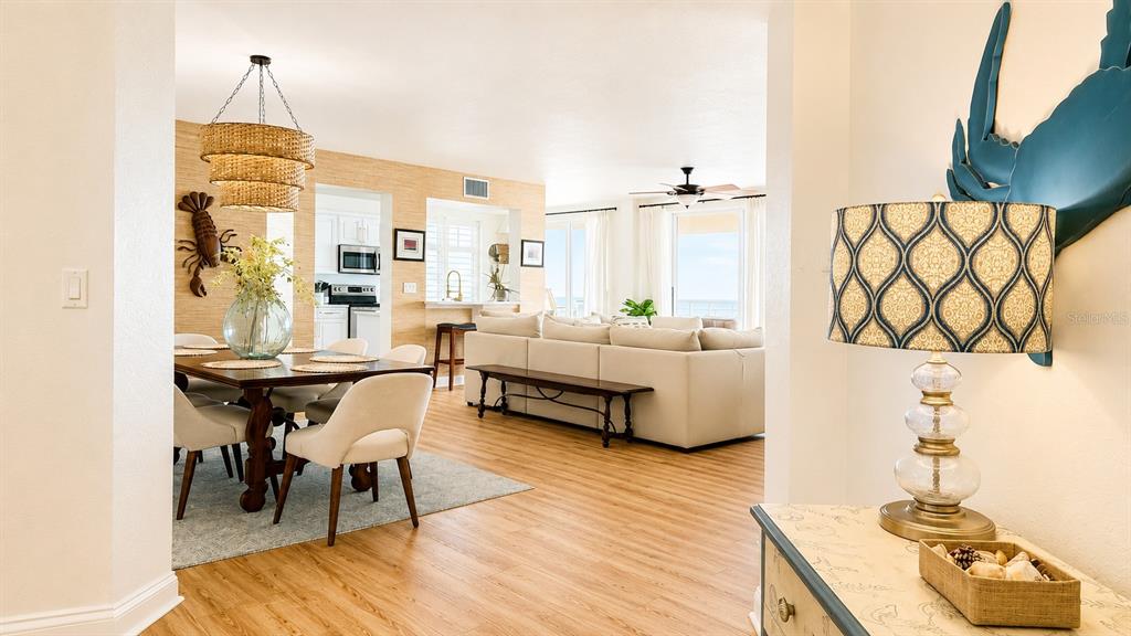 An open-concept living and dining area features light wood flooring and coastal-themed decor — 10 PAPAYA STREET UNIT 901, CLEARWATER BEACH, FL